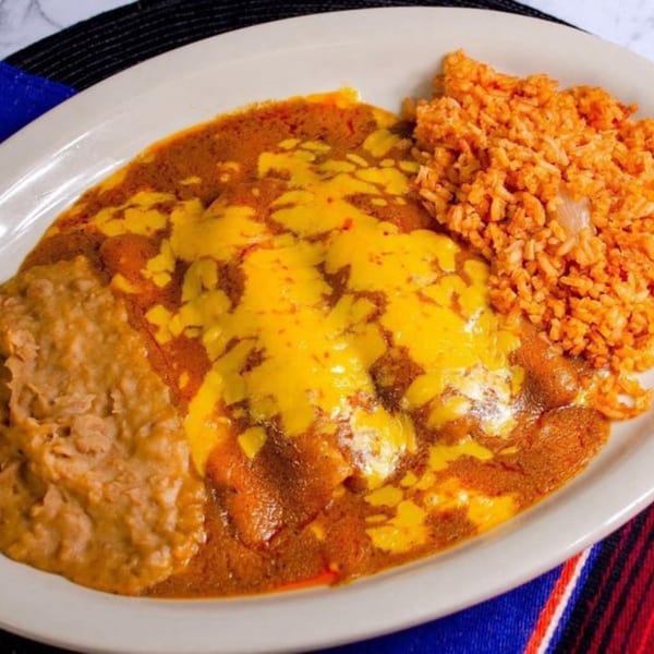 Mexican enchiladas covered in cheese and red sauce, served with refried beans and Spanish rice.