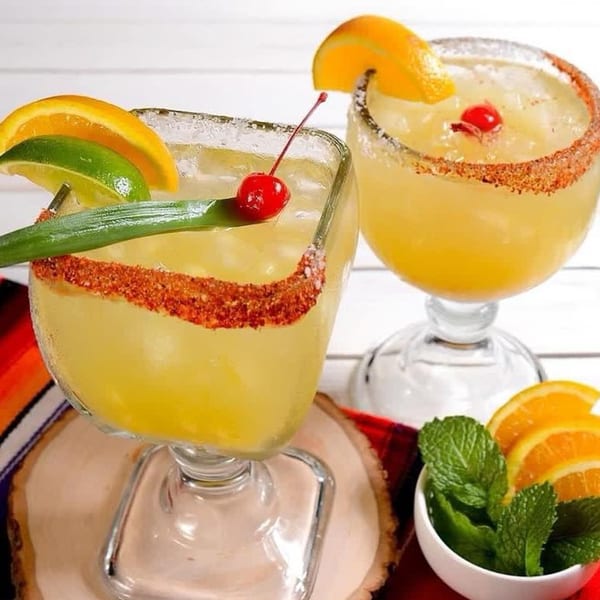 Two Margaritas & Fajitas Mexican Kitchen margaritas with chili-lime rims, garnished with fruit and cherries.
